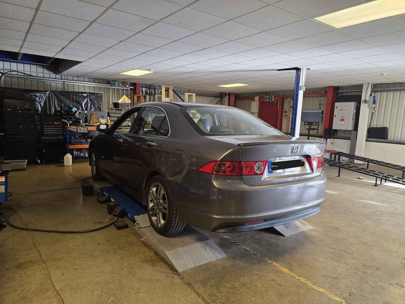 Grey Honda Accord on the lift ramps in the workshop