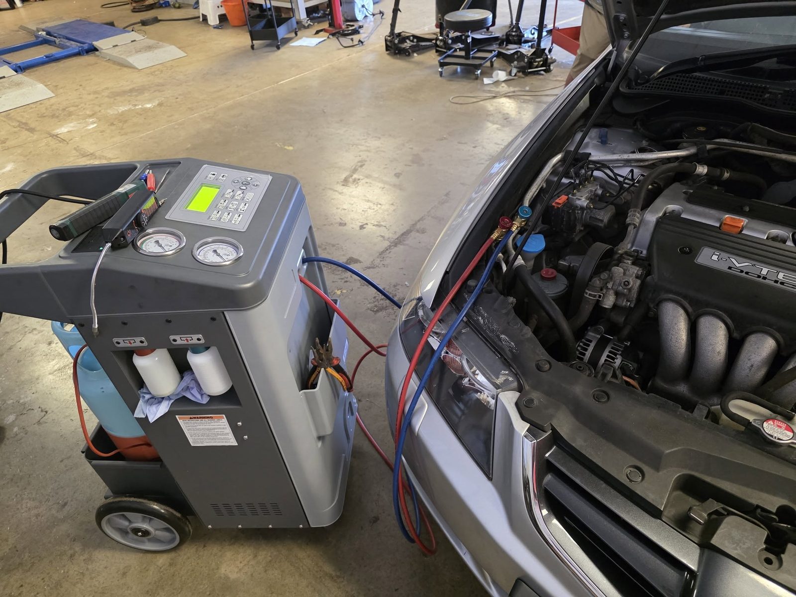 AC regas machine connected to a Honda engine bay