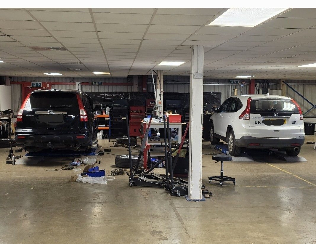 Two Hondas raised on lifts across the workshop floor