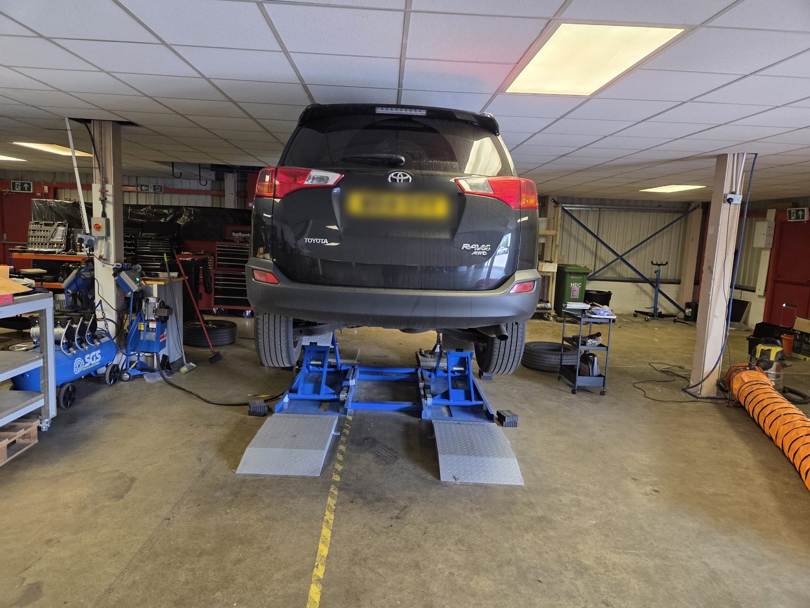 Toyota RAV4 on the lift with the workshop behind it